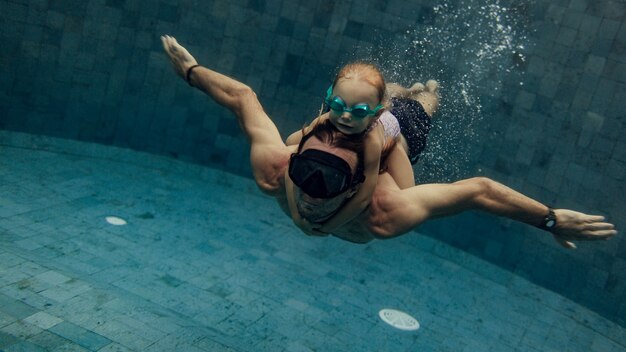 Padre e hija nadando juntos en la piscina