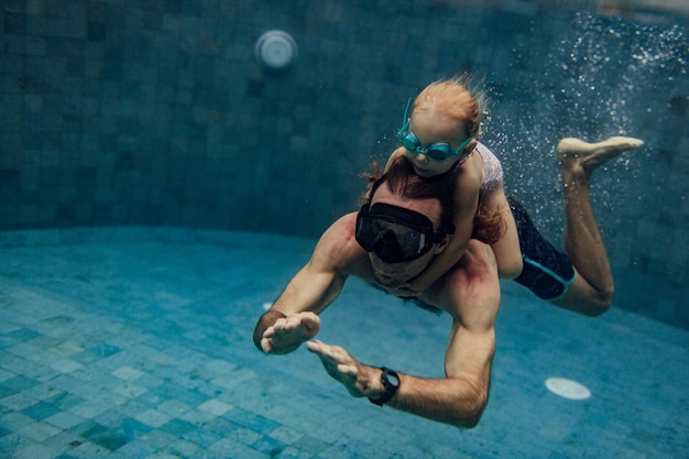 Padre e hija nadando juntos en la piscina