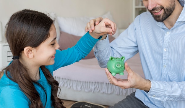 Padre e hija poniendo dinero en la hucha