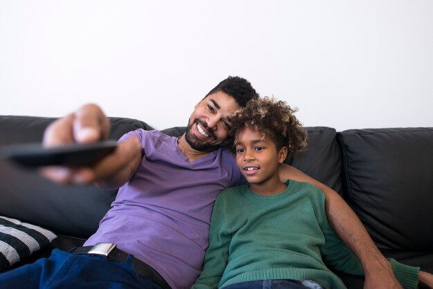 Padre e hija sentados en un cómodo sofá y viendo la televisión