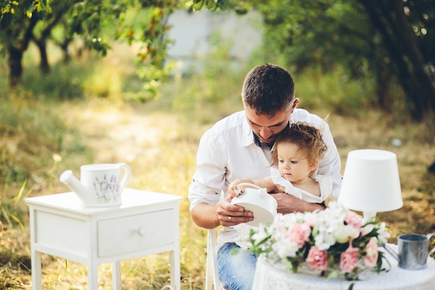 Foto gratuita padre e hija sentados en una silla blanca en el campo