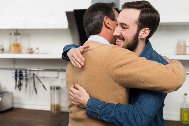 Padre e hijo abrazándose en la cocina