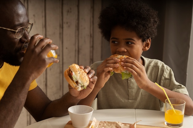 Padre e hijo almorzando juntos y disfrutando de hamburguesas y papas fritas