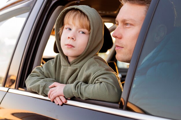 Foto gratuita padre e hijo en el coche admirando la vista durante un viaje por carretera