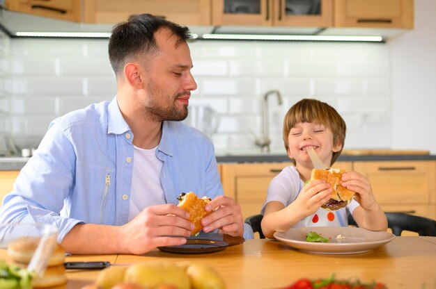 Padre e hijo comiendo deliciosas hamburguesas