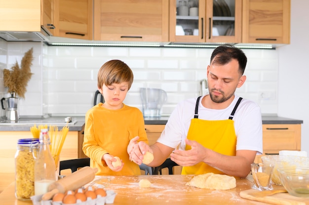 Padre e hijo creando bolas de masa vista frontal