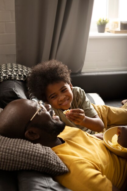 Padre e hijo disfrutando de bocadillos juntos en el sofá