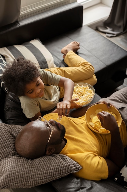 Padre e hijo disfrutando de palomitas de maíz juntos en el sofá