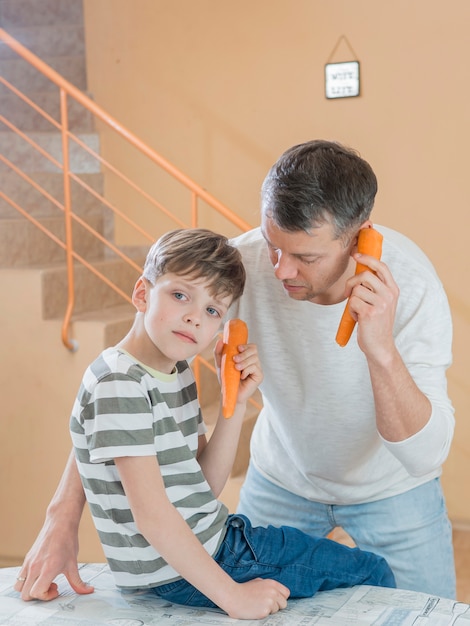 Padre e hijo hablando por teléfonos de zanahoria