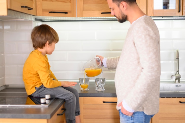 Padre e hijo haciendo y bebiendo jugo de naranja