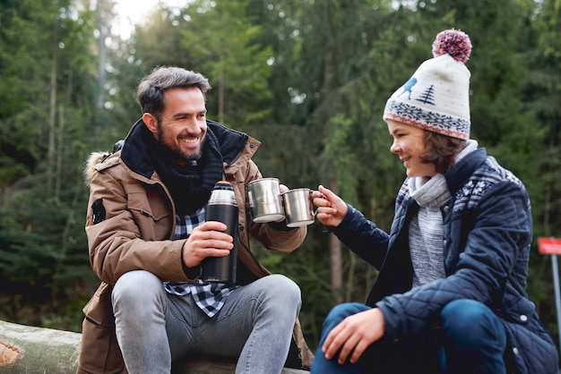 Foto gratuita padre e hijo haciendo un brindis en el bosque