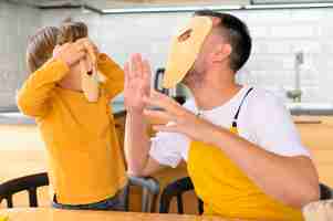 Foto gratuita padre e hijo haciendo máscaras de masa