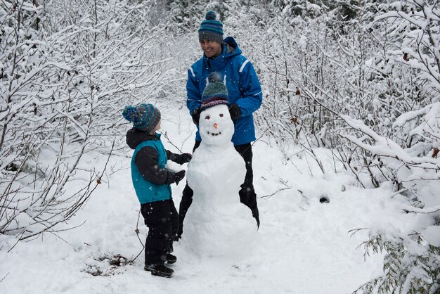 Padre e hijo haciendo muñeco de nieve