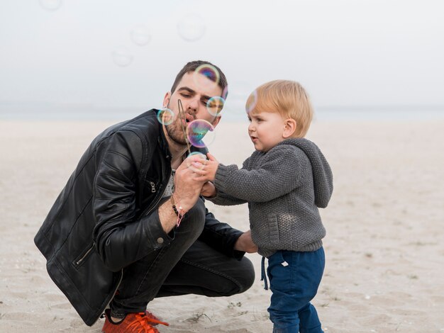 Padre e hijo haciendo pompas de jabón en la playa.