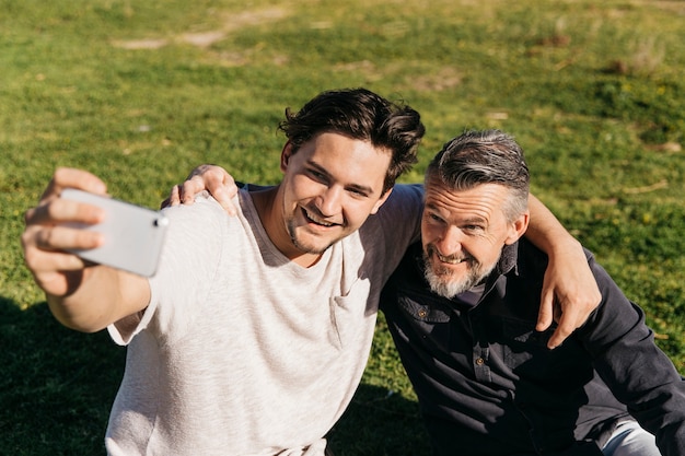 Padre e hijo haciendo selfie en césped