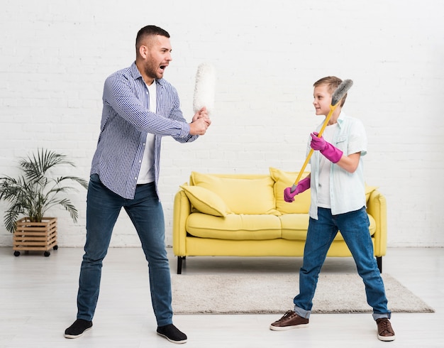 Foto gratuita padre e hijo juegan pelea con plumero y escoba