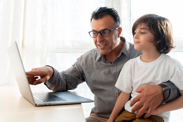 Padre e hijo jugando algo en un portátil.