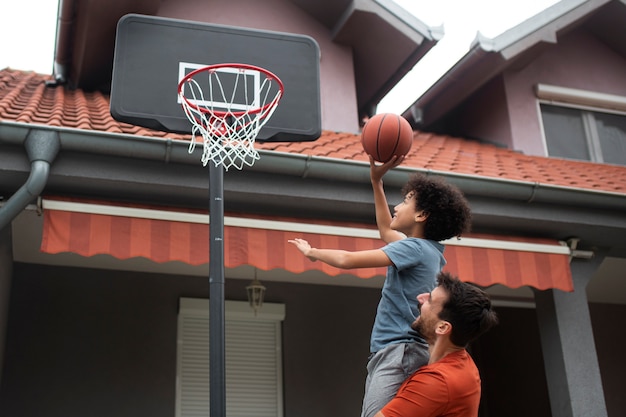 Padre e hijo jugando baloncesto juntos en casa en el patio trasero