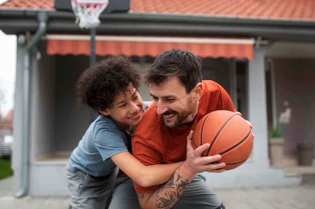 Foto gratuita padre e hijo jugando baloncesto juntos en casa en el patio trasero