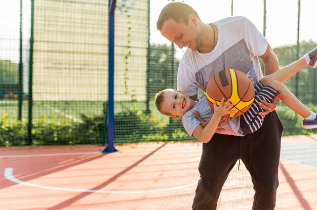 Padre e hijo jugando en el campo de baloncesto