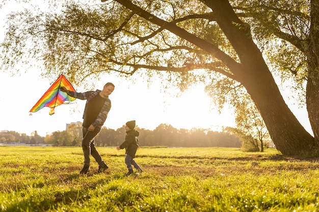 Padre e hijo jugando con una cometa en el parque