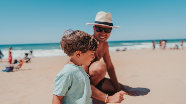 Padre e hijo jugando felizmente en la playa de arena