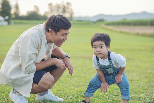 Padre e hijo jugando en el parque a la hora del atardecer. gente divirtiéndose en el campo. concepto de familia amistosa y de vacaciones de verano. padre e hijo, piernas, caminar, por, el, césped, en, el, parque