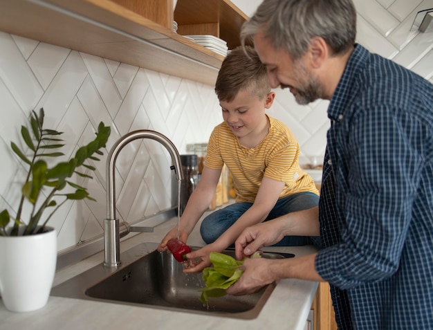 Foto gratuita padre e hijo lavando verduras