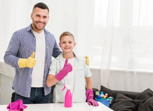 Padre e hijo levantando los pulgares mientras limpiaban la casa