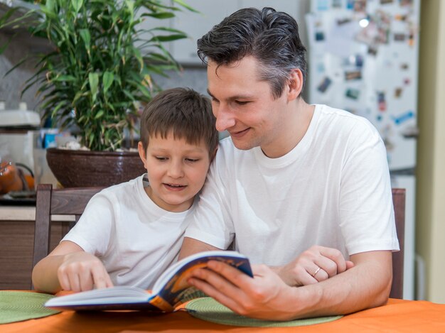 Padre e hijo leyendo un libro plano medio