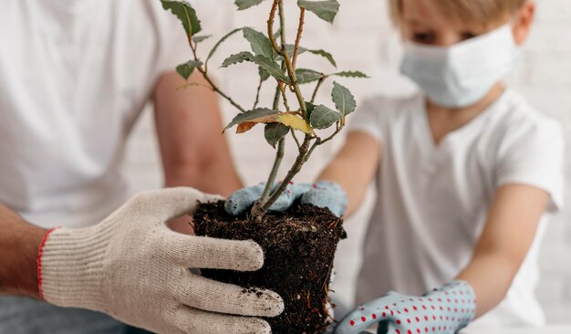 Padre e hijo con máscaras médicas y aprender a plantar