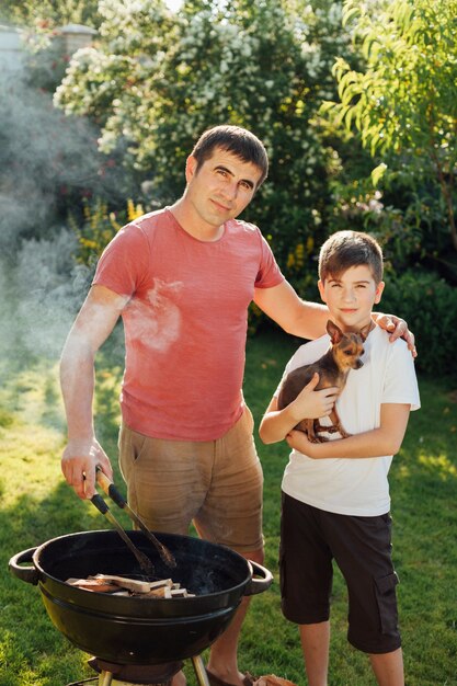 Padre e hijo mirando a cámara durante la cocción en barbacoa en el parque