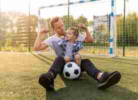 Foto gratuita padre e hijo, mostrando los músculos en el campo de fútbol