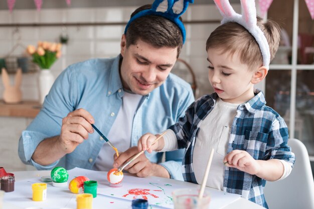 Padre e hijo pintando huevos para pascua juntos