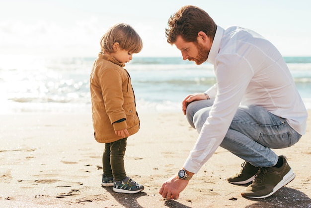 Foto gratuita padre e hijo recogiendo guijarros