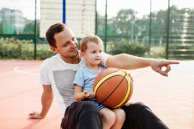 Padre e hijo relajándose en el campo de baloncesto