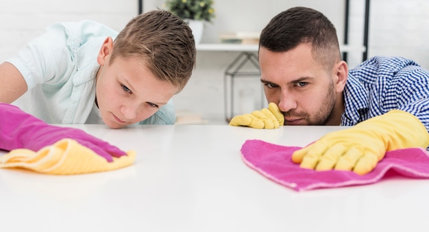 Foto gratuita padre e hijo siendo precisos mientras limpian