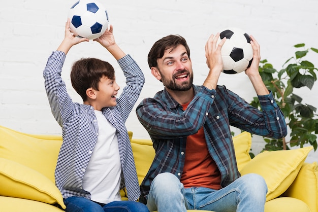 Foto gratuita padre e hijo sosteniendo balones de fútbol