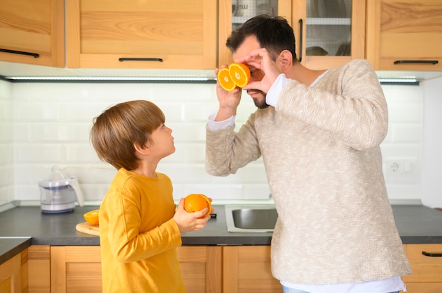 Padre e hijo sosteniendo mitades de naranjas