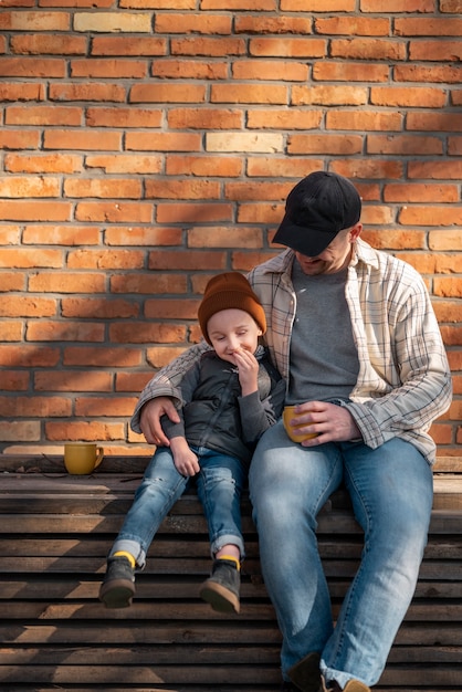 Padre e hijo de tiro completo sentados al aire libre