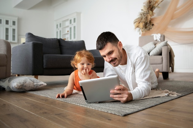 Padre e hijo de tiro completo con tableta en el piso