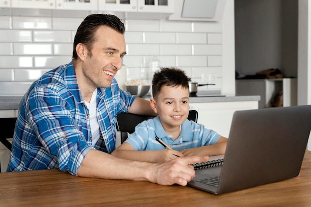 Foto gratuita padre e hijo de tiro medio con laptop