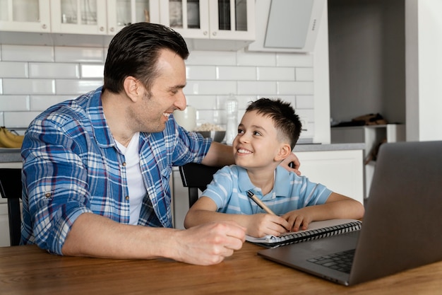 Foto gratuita padre e hijo de tiro medio con laptop