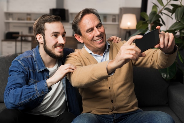 Padre e hijo tomando selfie en sala de estar