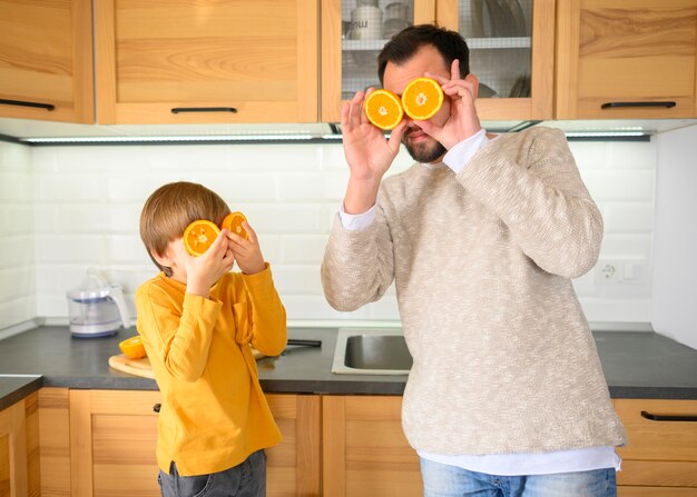 Padre e hijo usando mitades de naranjas para cubrir sus ojos