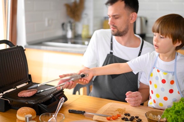 Foto gratuita padre e hijo volteando la hamburguesa alta vista