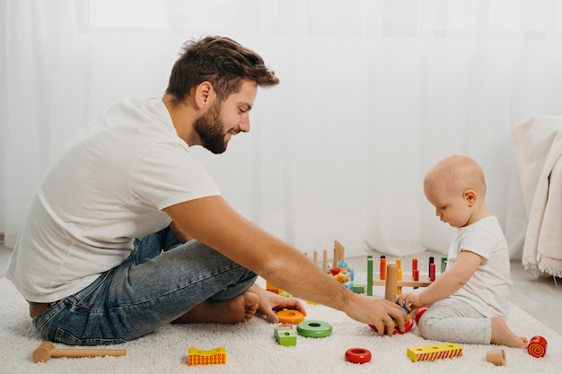 Padre enseñando al bebé a jugar con juguetes en casa