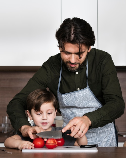 Padre enseñando a hijo a cortar tomate