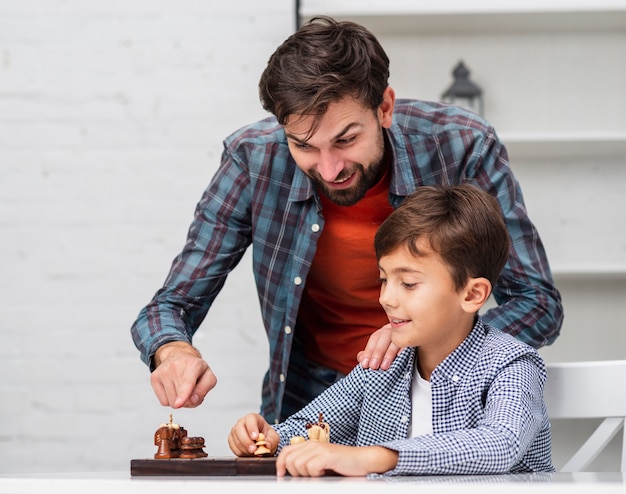 Foto gratuita padre enseñando a hijo a jugar al ajedrez