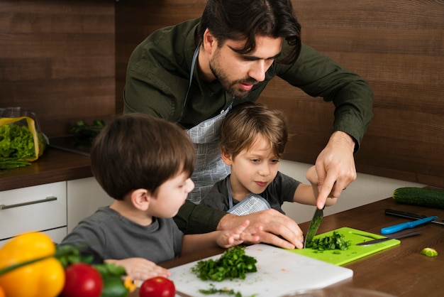 Padre enseñando a hijos a cortar verduras